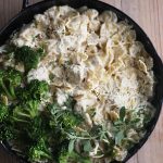 cast iron skillet loaded with chicken pasta and alfredo sauce topped with spinach