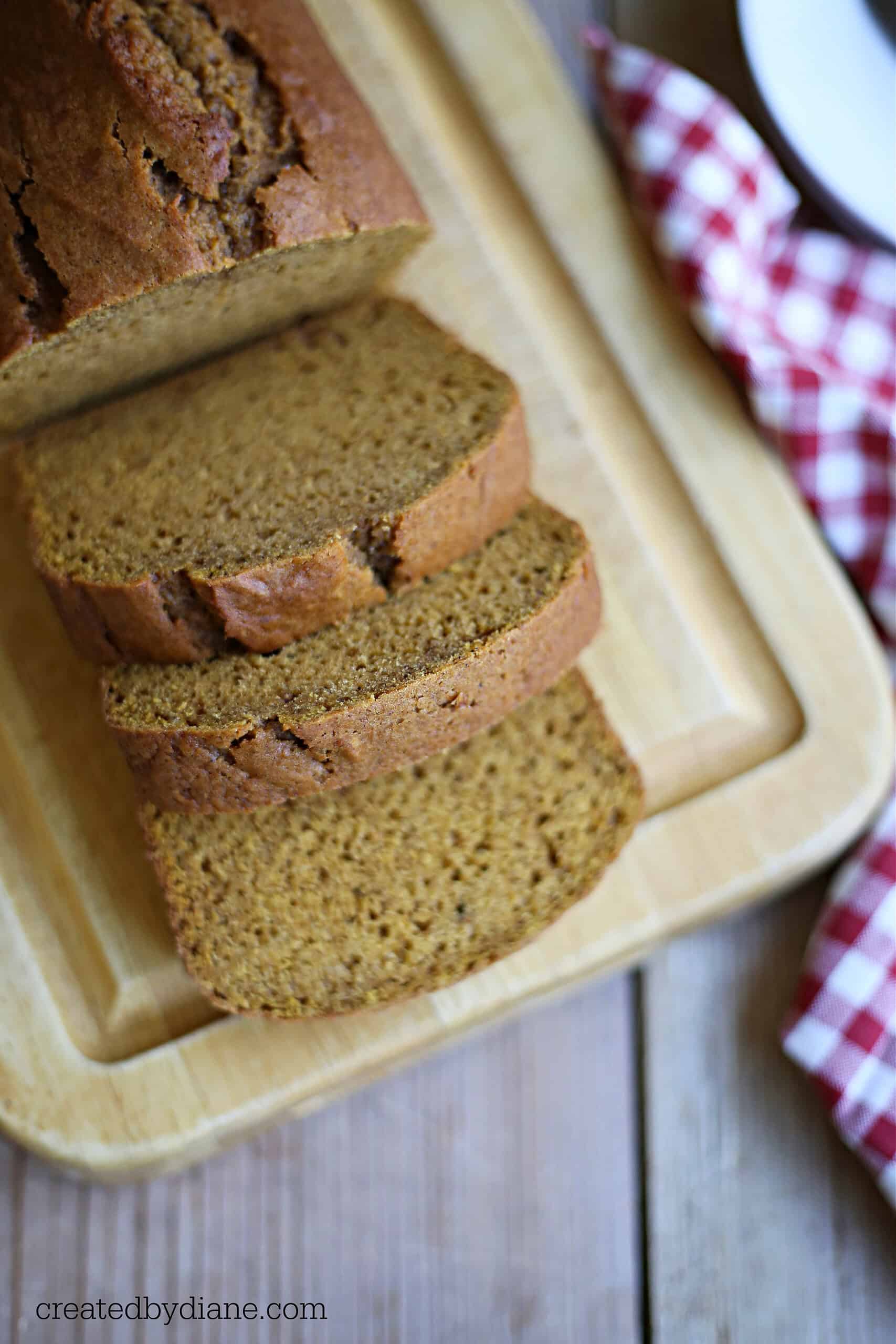 sliced pumpkin bread on a wood chopping board, with a red and white checked napkin